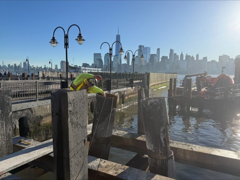 FTG technician performing Crosshole Sonic Logging (CSL) testing on drilled shaft foundations with the Manhattan skyline in the background.